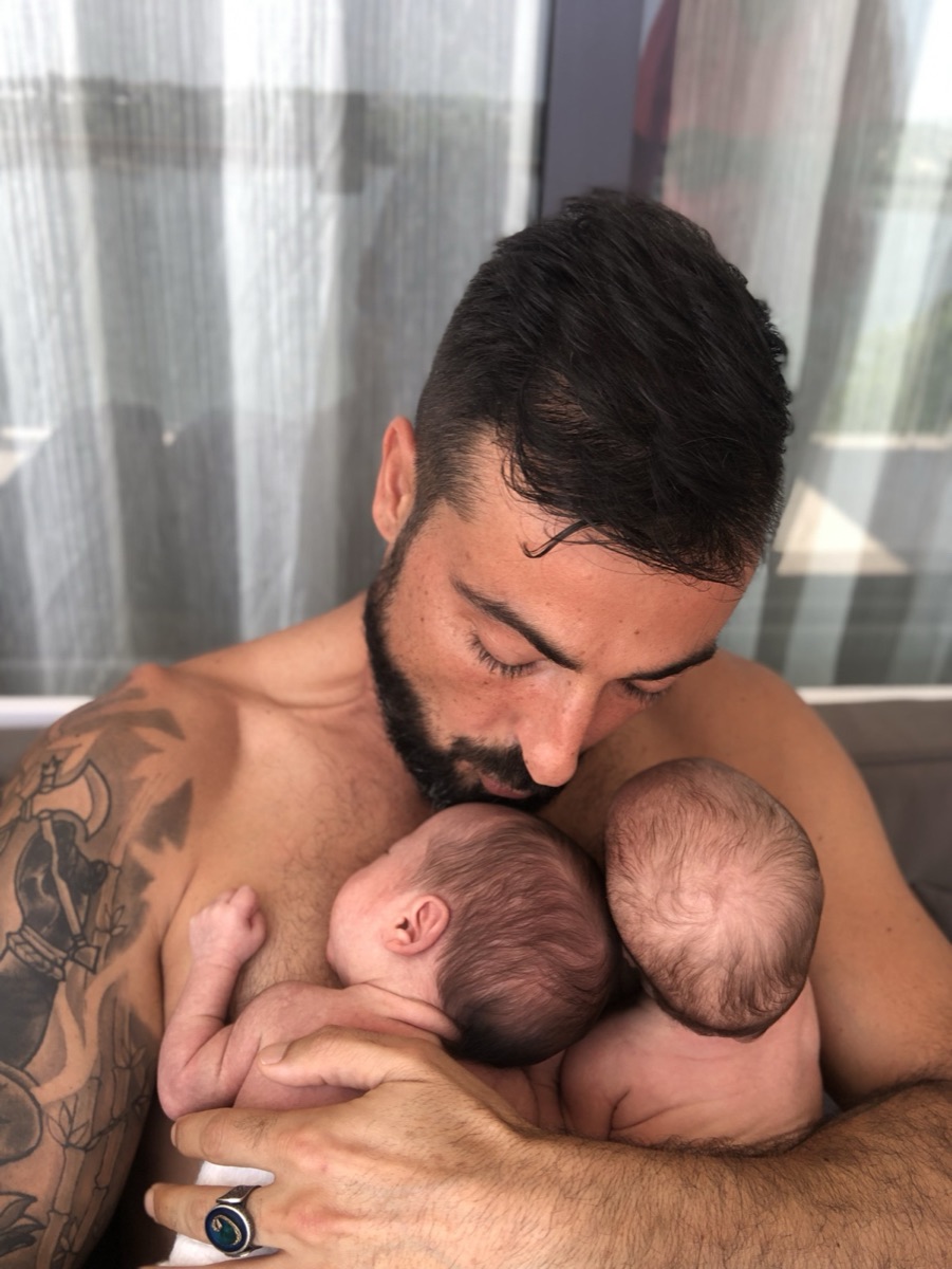 Joseph Tito holding his newborn twin daughters